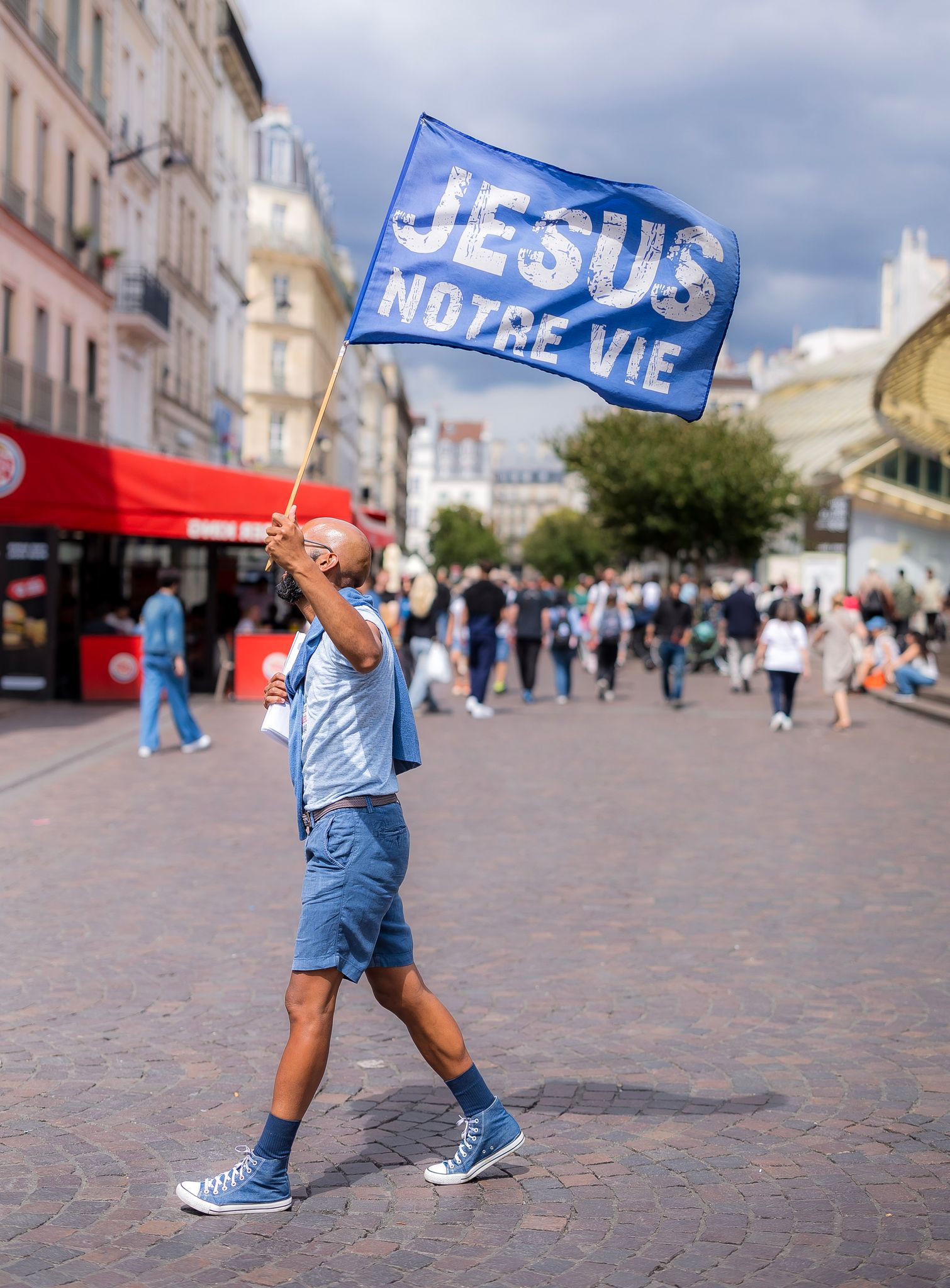 A French Christian missionary waves the flag "Jesus is our Life" in the center of a bustling intersection