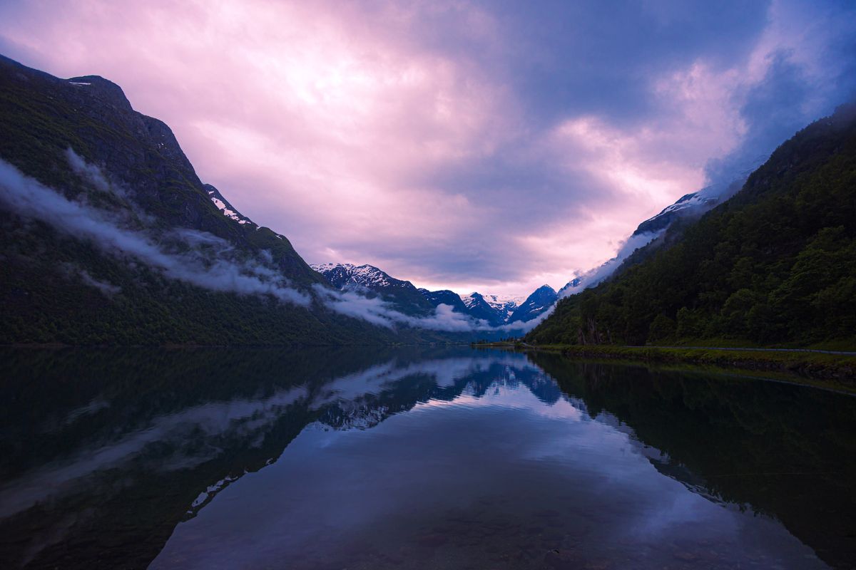 A serene lake called Oldevatnet in Norway. The purple tint comes from a combination of the evening light and the bus window through which the photo was captured