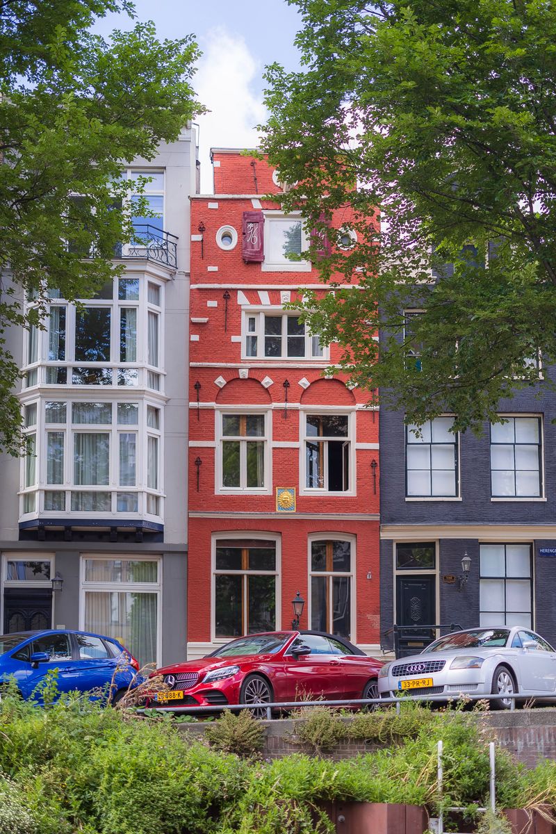 Three colorful buildings and cars on the canals by De Negen Straatjes (The Nine Bridges) in Amsterdam