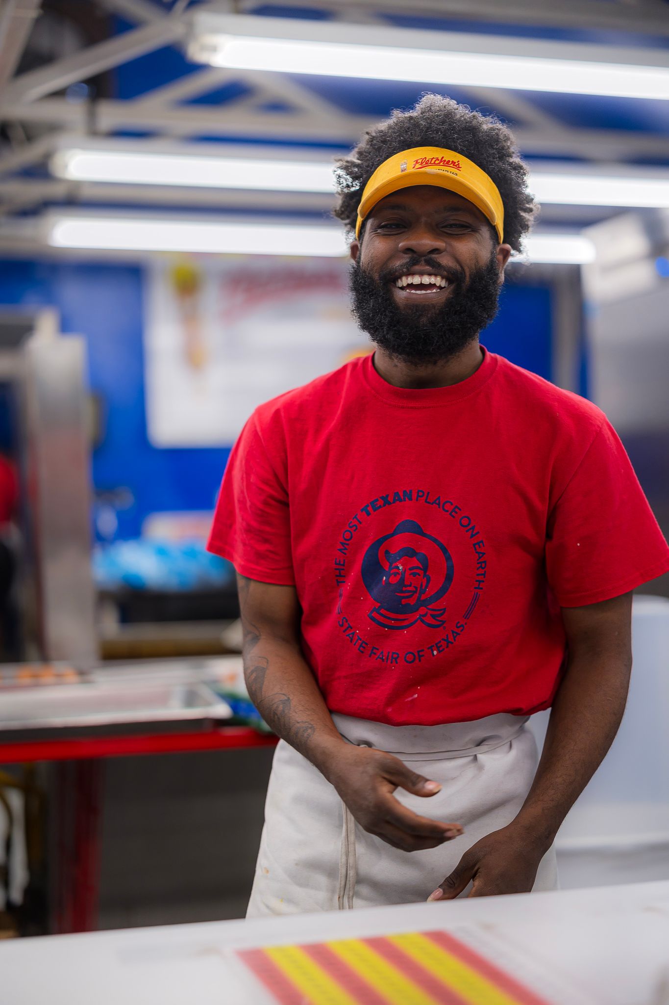 A worker at the State Fair of Texas prepares to serve a corn dog with a smile